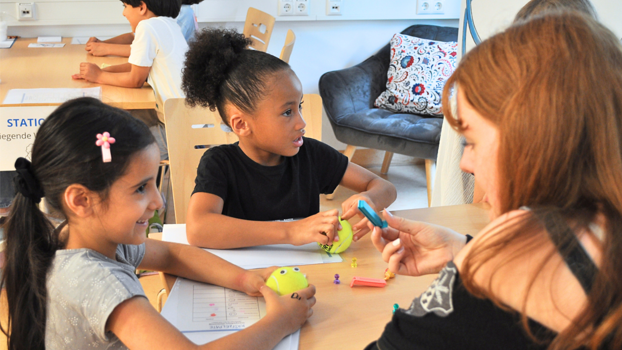Kinder probieren beim Aktionstag "Spielerisch fit fürs Schreiben" die Übung "der hungrige Tennisball" aus.