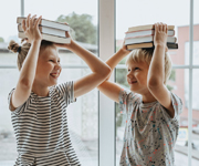 Zwei Kinder halten Bücher über ihren Köpfen, Copyright: Pexels/Olia Danilevich