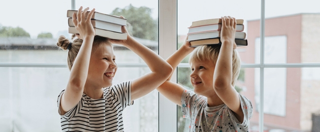 Zwei Kinder halten Bücher über ihren Köpfen, Copyright: Pexels/Olia Danilevich